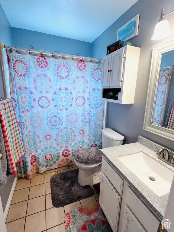 Full bathroom with a shower with shower curtain, tile patterned floors, vanity, and toilet