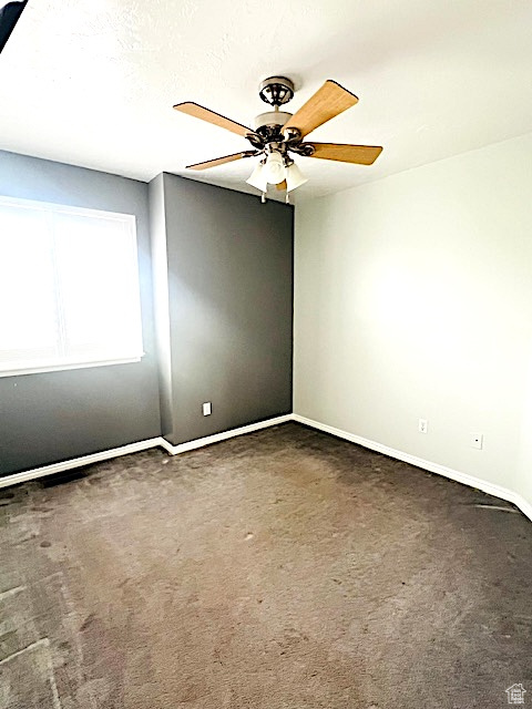 Carpeted empty room featuring baseboards and ceiling fan