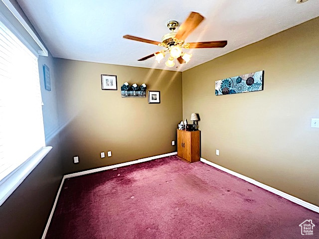 Empty room featuring carpet flooring, baseboards, and ceiling fan