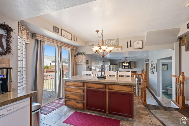 Kitchen featuring stone countertops, an inviting chandelier, a kitchen island, dishwasher, and hanging light fixtures