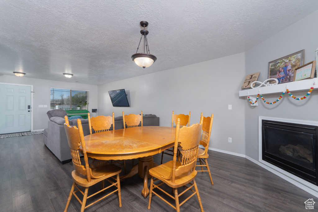 Dining area featuring a textured ceiling, wood finished floors, and baseboards