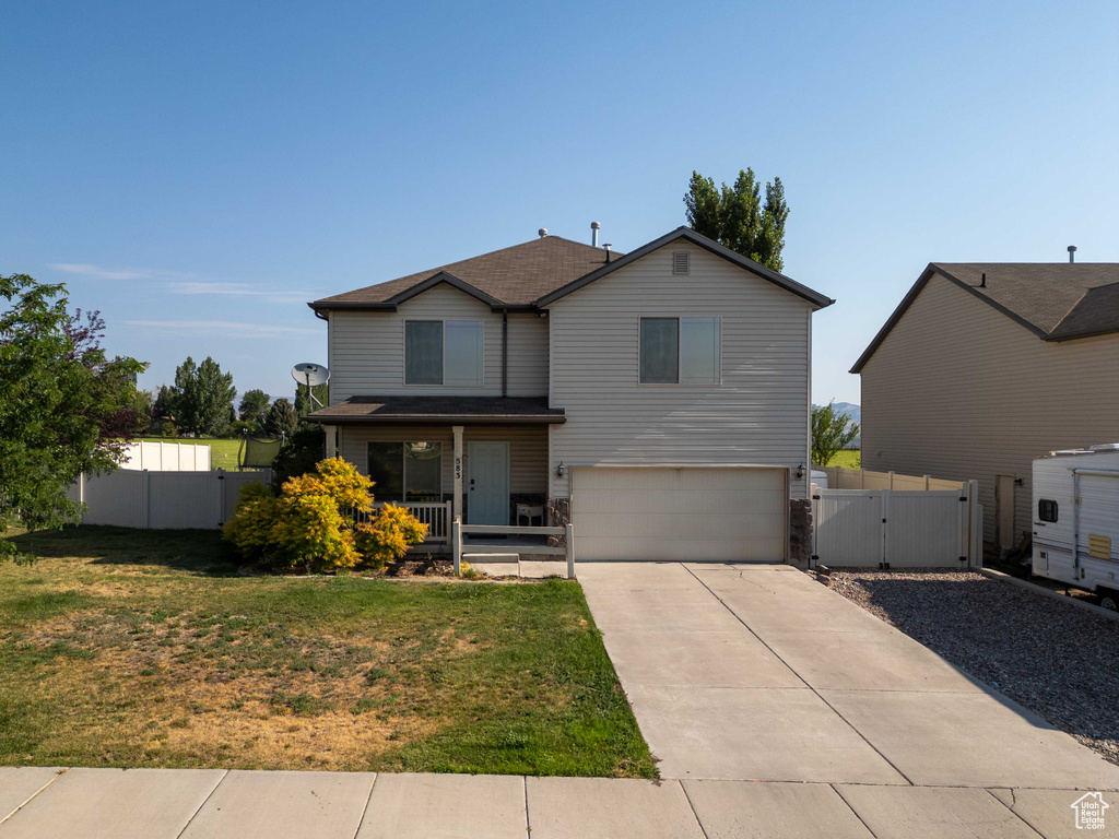 Traditional-style house with a gate, concrete driveway, a garage, and covered porch