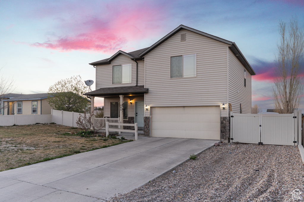 Traditional-style home with a garage, a porch, fence, a gate, and concrete driveway