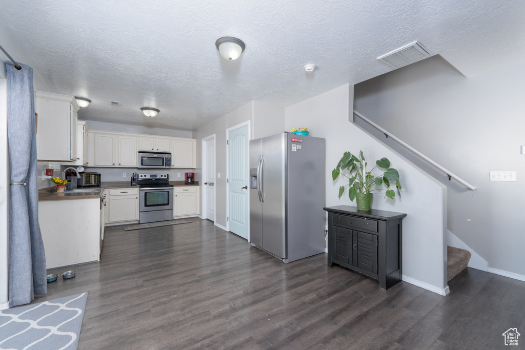Kitchen featuring a sink, dark wood finished floors, visible vents, and stainless steel appliances