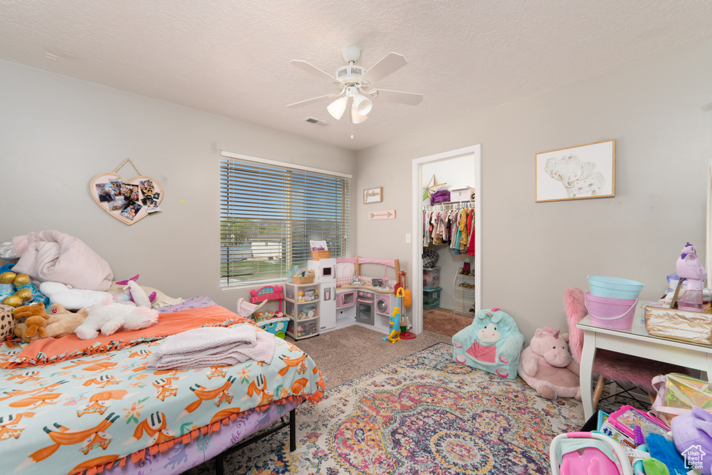 Bedroom featuring a closet, visible vents, a spacious closet, a ceiling fan, and carpet floors