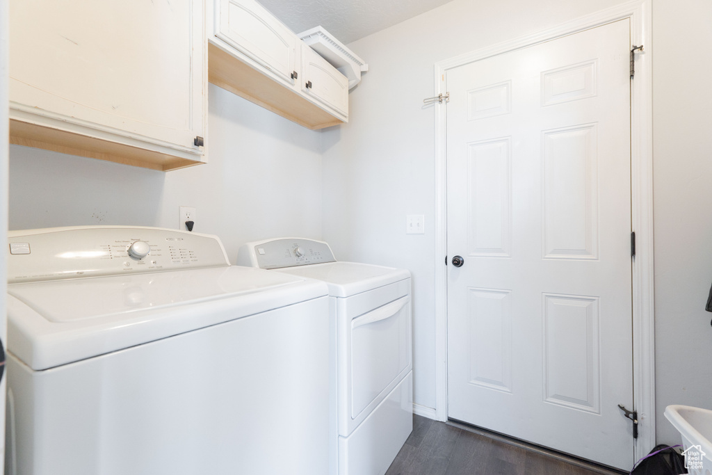 Laundry area featuring dark wood-type flooring, cabinet space, and washing machine and dryer