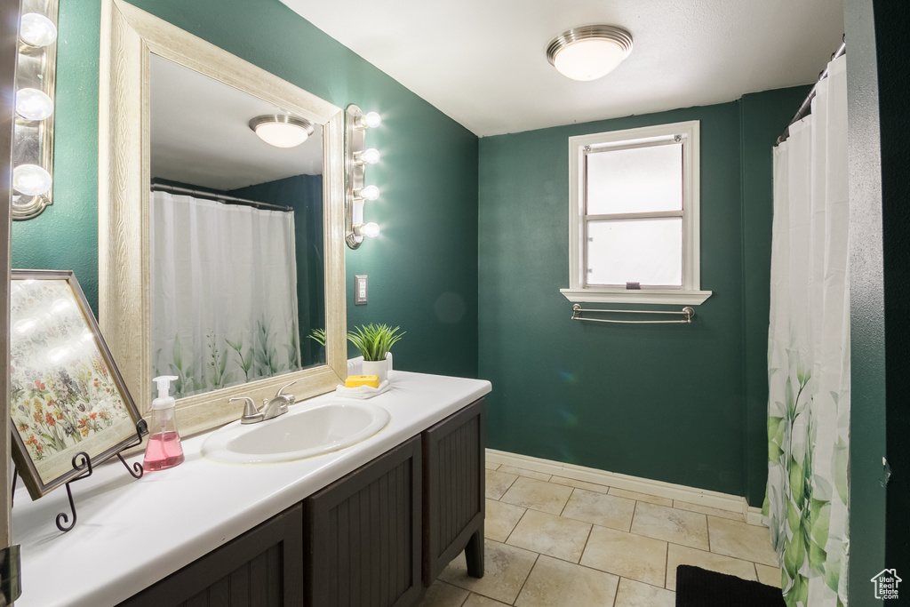 Full bath featuring tile patterned floors, vanity, and baseboards