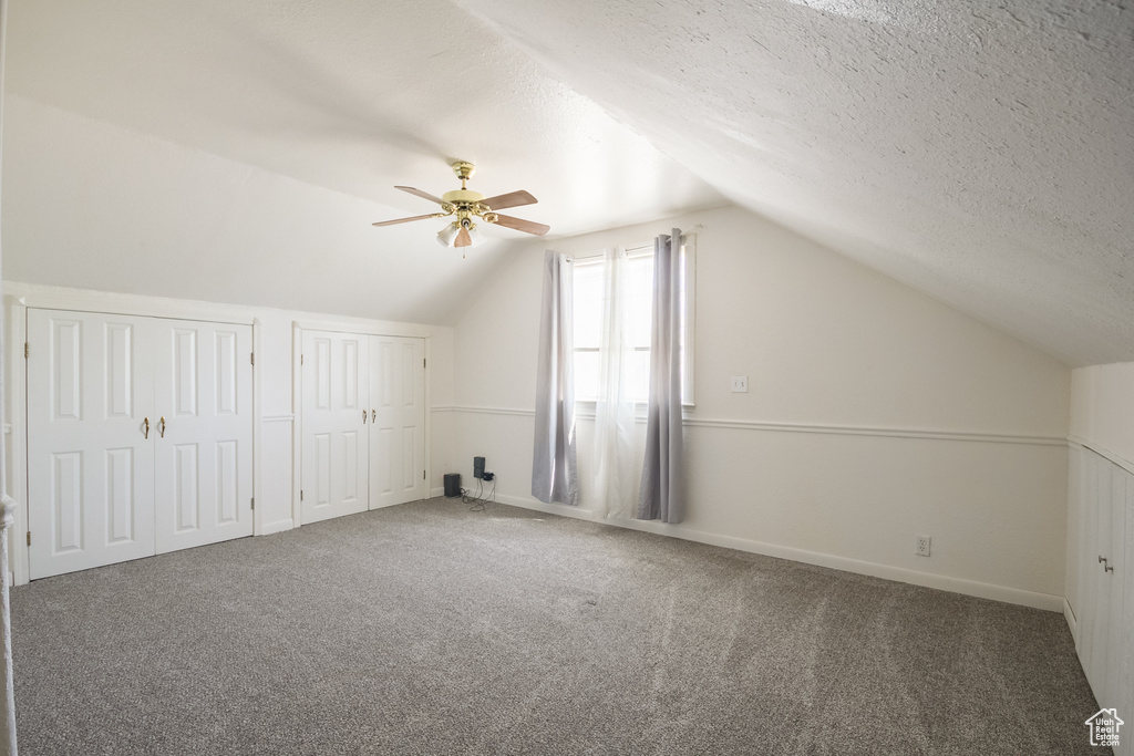 Bonus room with a ceiling fan, carpet, vaulted ceiling, and a textured ceiling