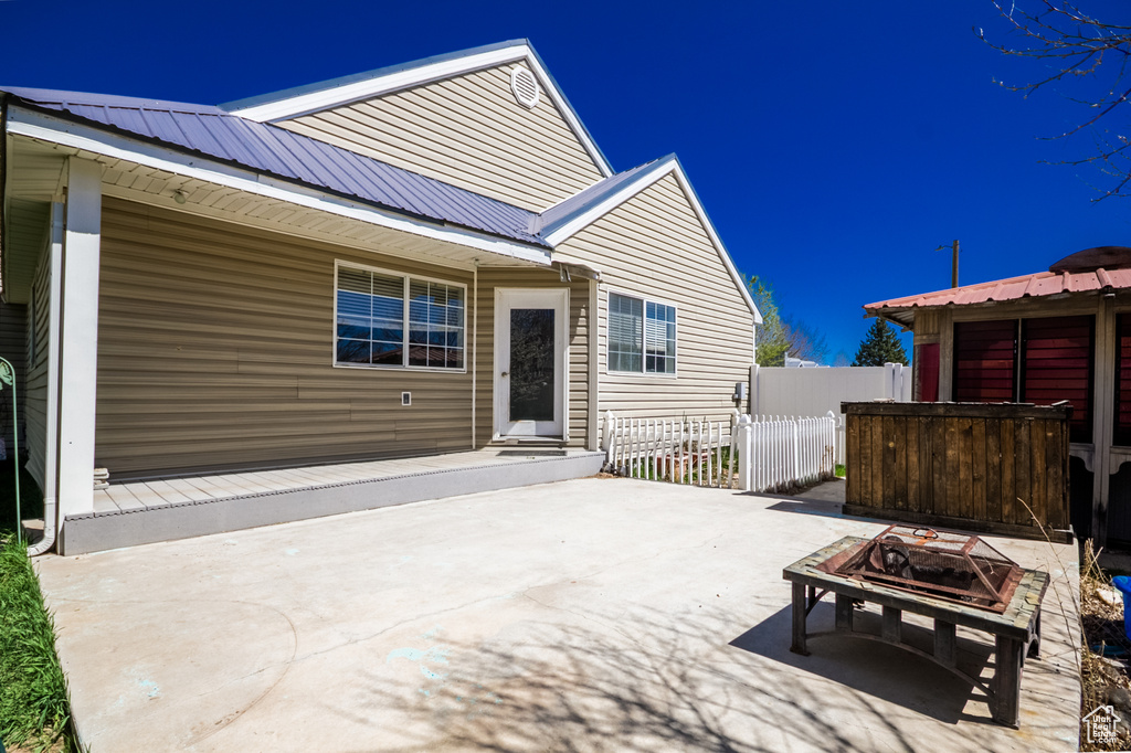 Rear view of house with a patio, metal roof, and fence