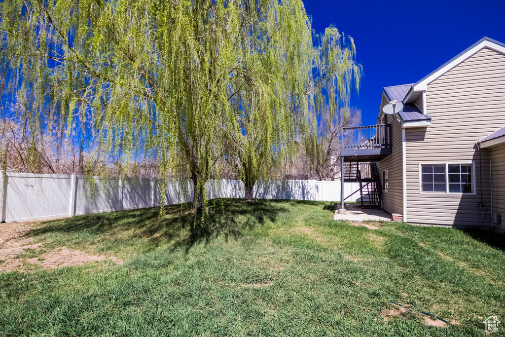View of yard with a fenced backyard, a deck, and stairs