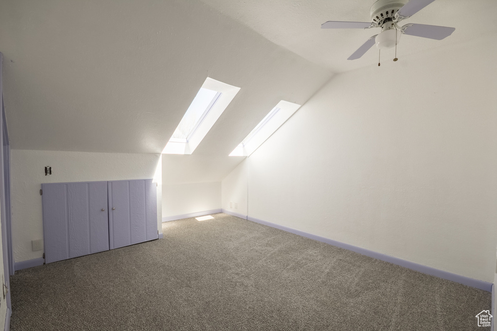 Bonus room with vaulted ceiling with skylight, baseboards, a ceiling fan, and carpet