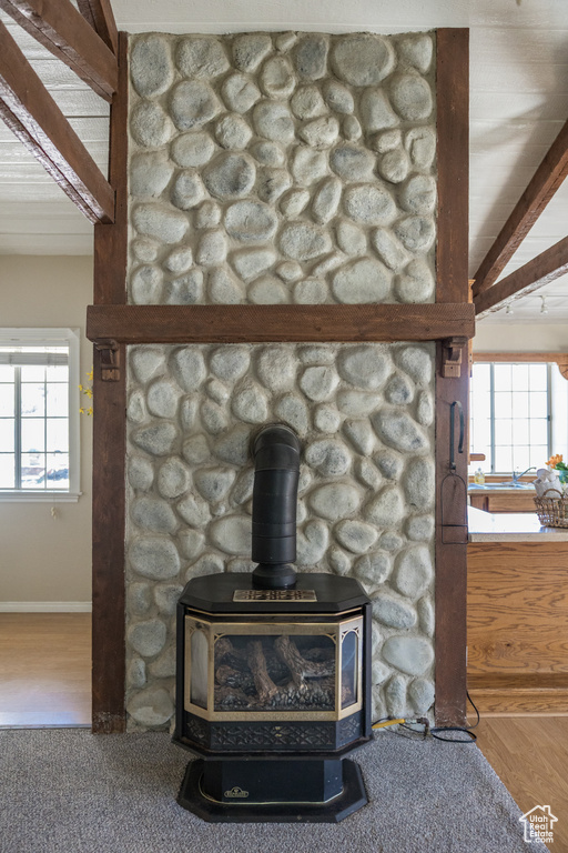 Details with wood finished floors, a wood stove, baseboards, and beam ceiling
