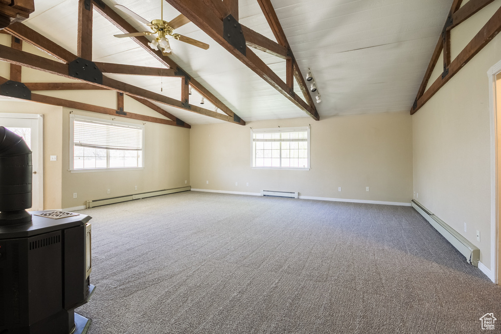 Unfurnished living room with a wood stove, a baseboard radiator, carpet, and a baseboard heating unit