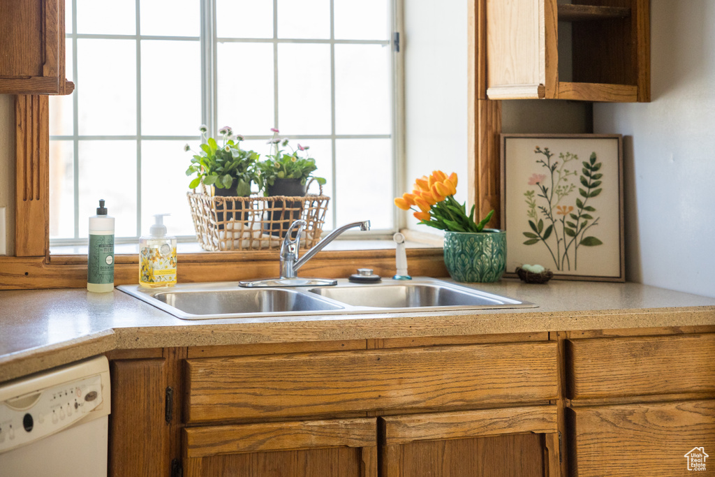 Kitchen with light countertops, brown cabinets, dishwasher, and a sink