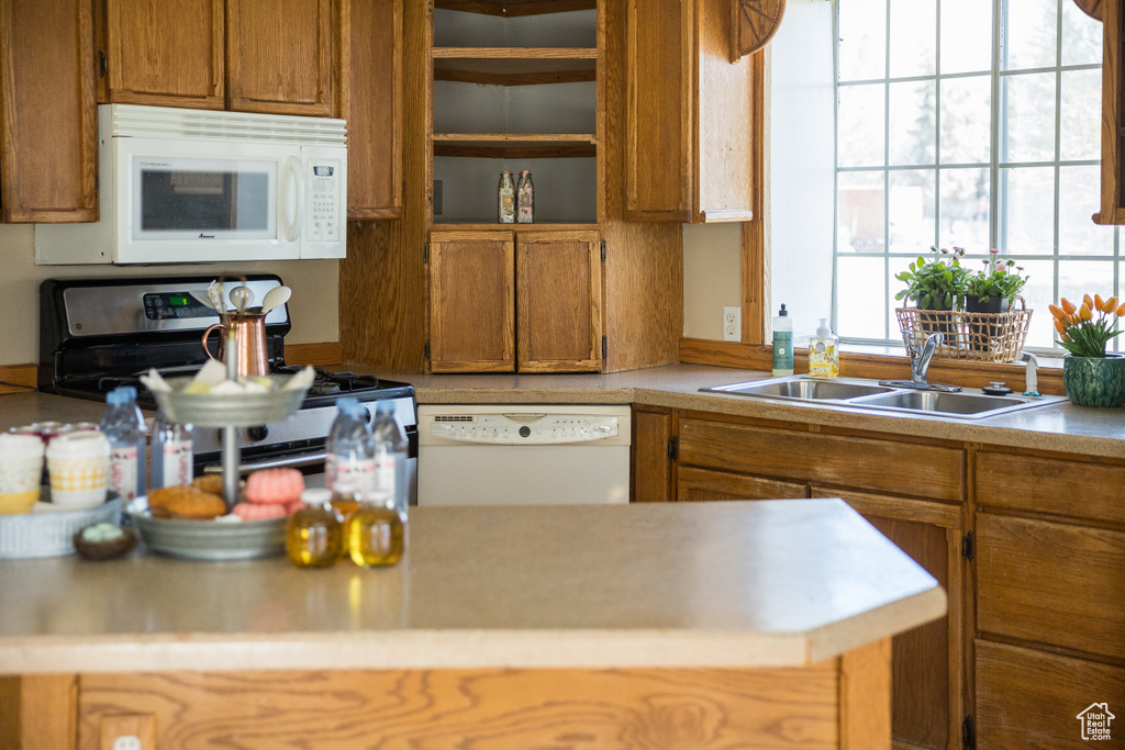 Kitchen featuring white appliances, open shelves, light countertops, a sink, and brown cabinets