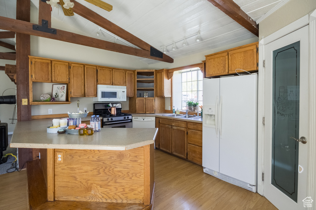 Kitchen featuring lofted ceiling with beams, white appliances, open shelves, light countertops, and a sink