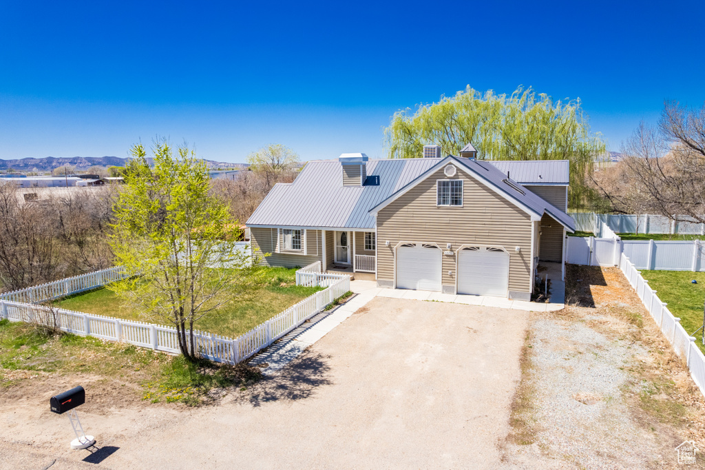 View of front of home featuring dirt driveway, a fenced backyard, metal roof, a front lawn, and a chimney