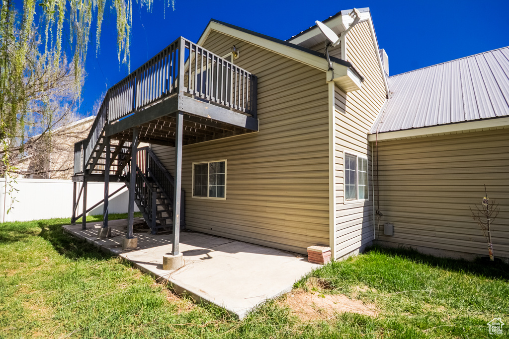 Back of house with a patio, stairway, a wooden deck, fence, and a lawn