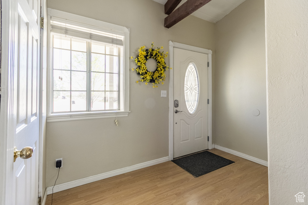Foyer with baseboards, light wood finished floors, beamed ceiling, and plenty of natural light