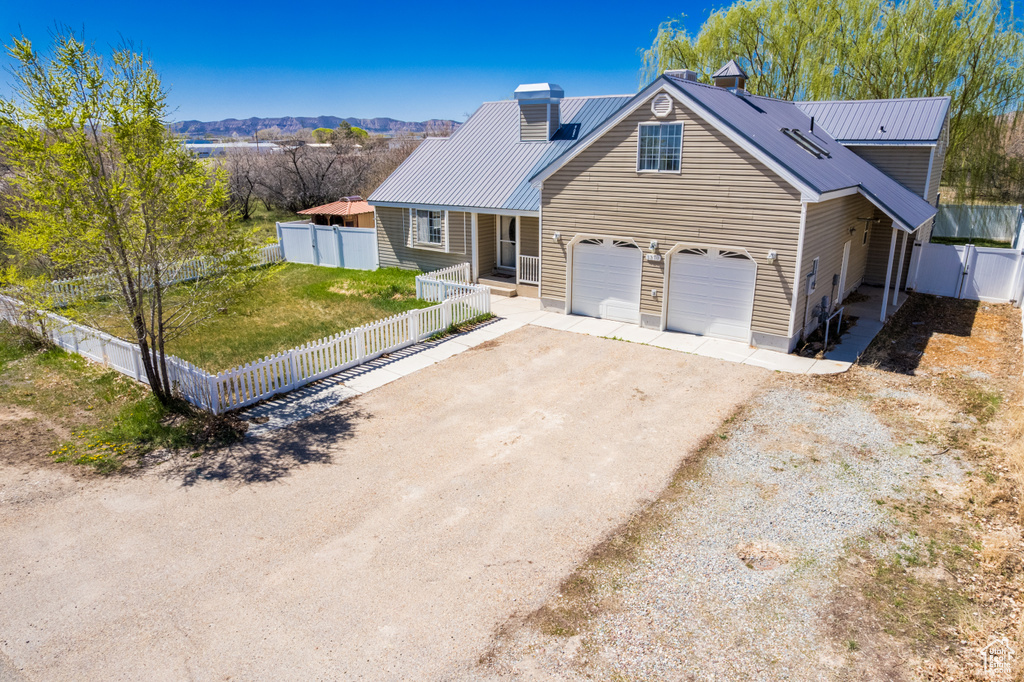 View of front of home with metal roof, driveway, fence, and a chimney