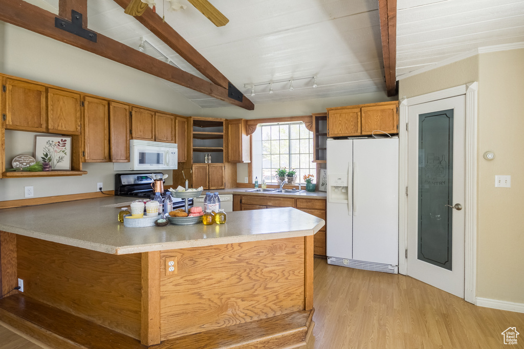 Kitchen with white appliances, open shelves, light wood-style floors, brown cabinetry, and a sink