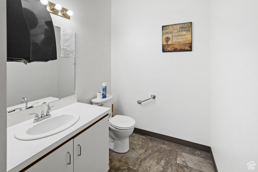 Bathroom with stone finish flooring, vanity, baseboards, and toilet