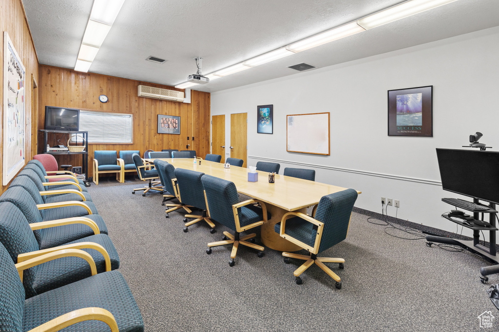 Office space with wood walls, carpet flooring, and visible vents