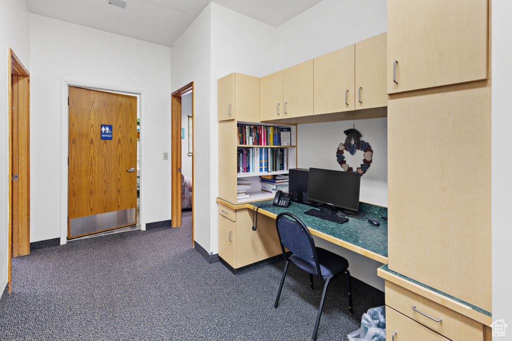 Home office with built in desk, baseboards, and carpet floors