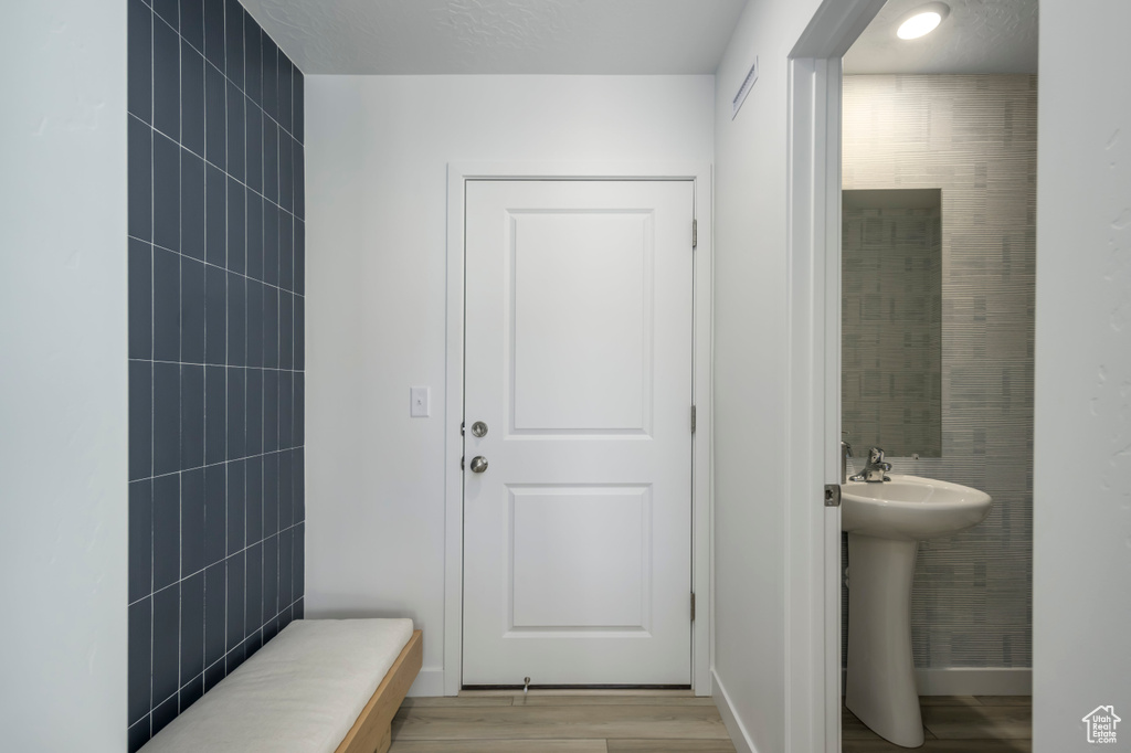 Bathroom with wood finished floors, a sink, and tile walls