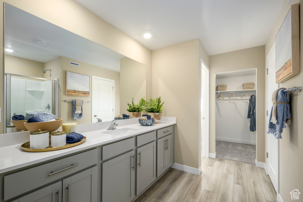 Bathroom featuring a shower stall, vanity, a spacious closet, visible vents, and wood finished floors