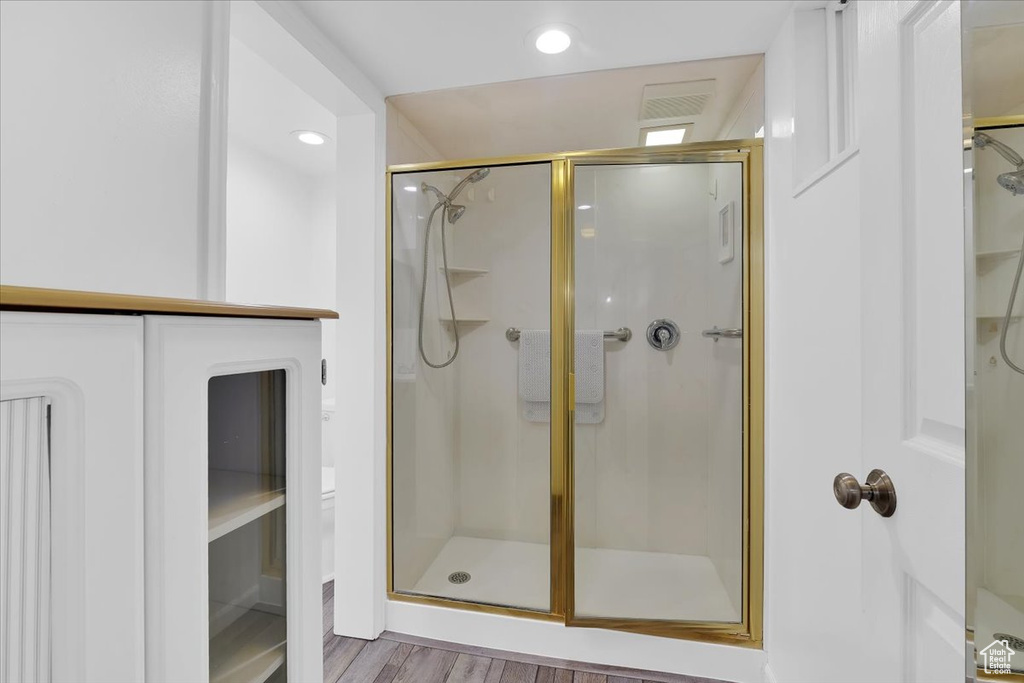 Full bath featuring a shower stall, recessed lighting, visible vents, and wood finished floors