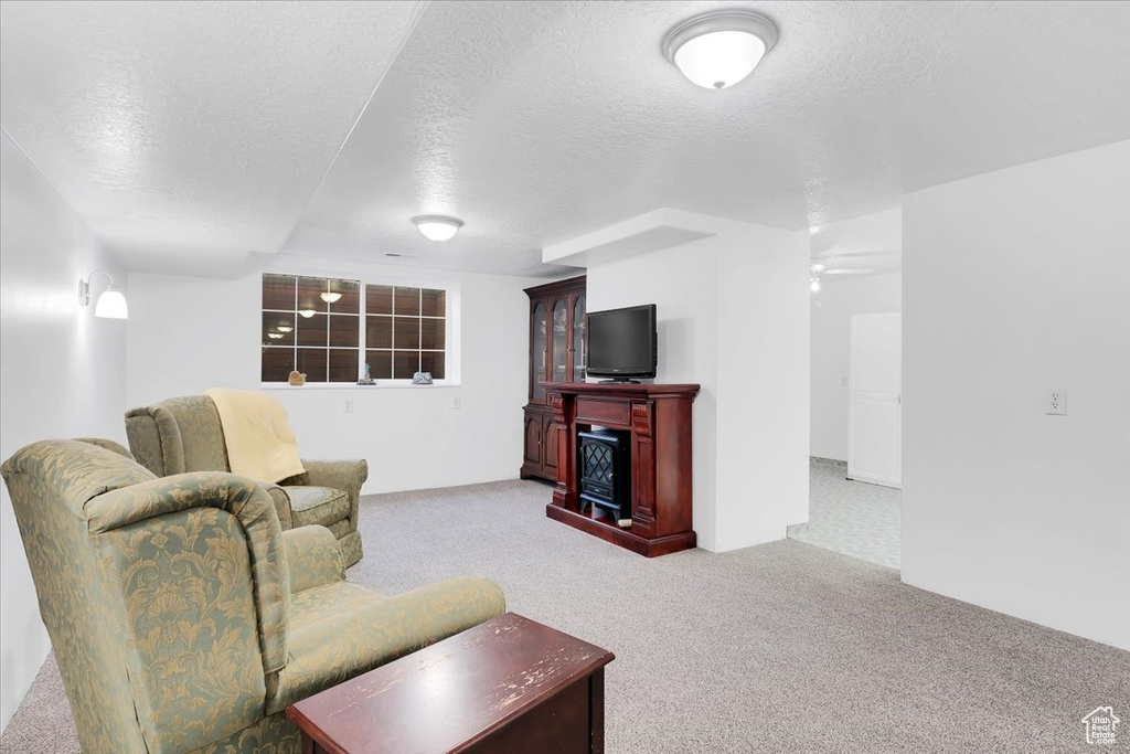 Living area with a ceiling fan, carpet, a fireplace, and a textured ceiling