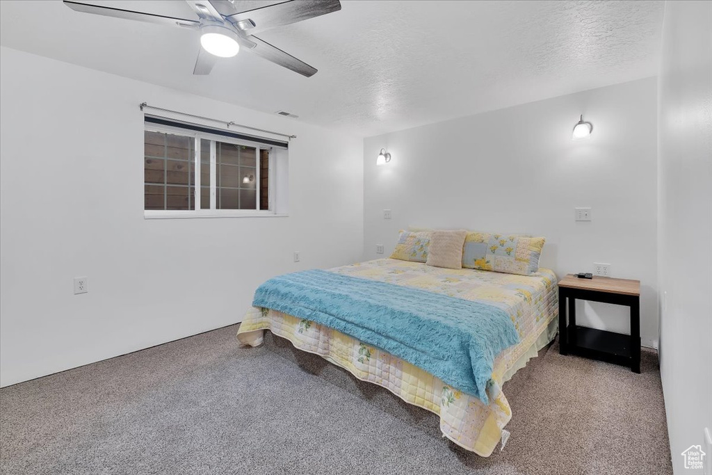 Bedroom with a textured ceiling, visible vents, ceiling fan, and carpet