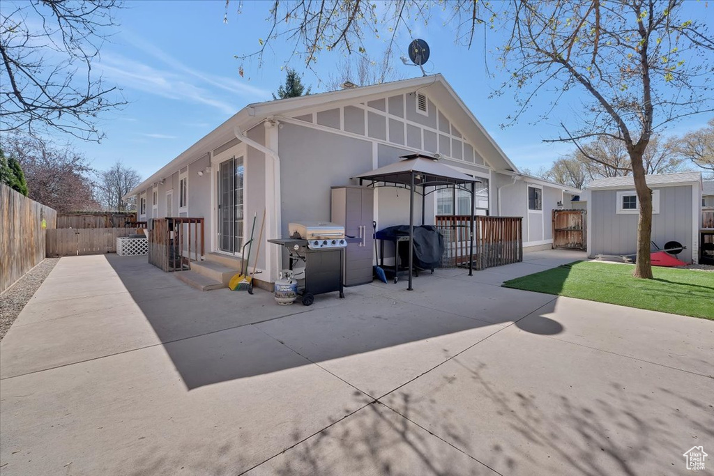 Rear view of house with a patio, stucco siding, a fenced backyard, an outbuilding, and a gazebo