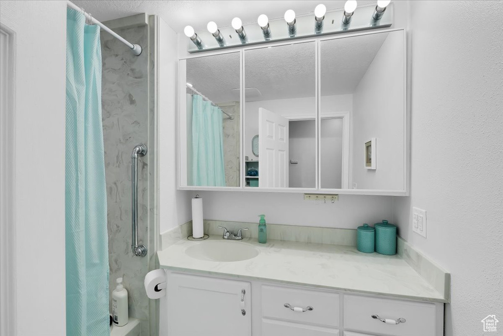 Bathroom featuring vanity, a textured ceiling, and curtained shower