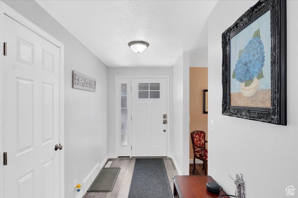 Doorway with visible vents, baseboards, wood finished floors, and a textured ceiling