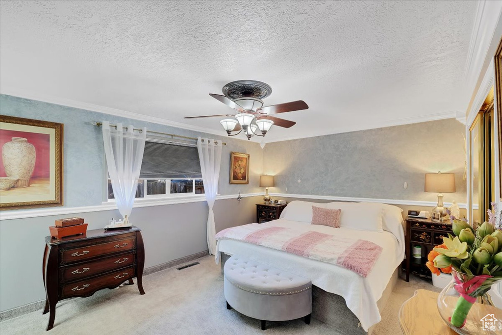 Bedroom with a textured ceiling, crown molding, carpet floors, visible vents, and ceiling fan