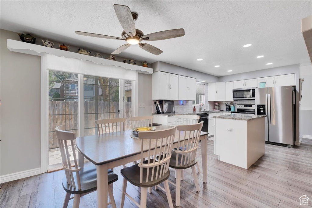 Dining space featuring light wood-style flooring, baseboards, a textured ceiling, and ceiling fan