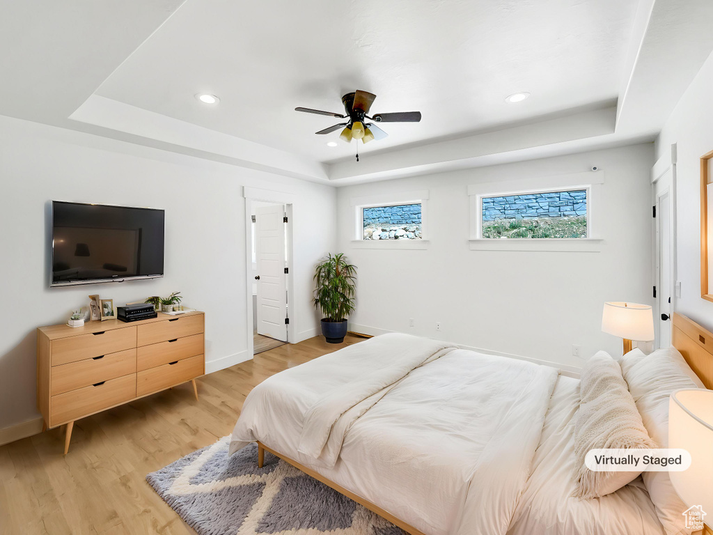 Bedroom featuring recessed lighting, baseboards, a raised ceiling, and light wood-style floors