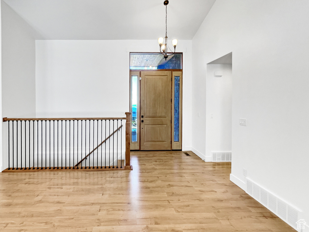Foyer entrance with light wood-style floors, a notable chandelier, visible vents, and baseboards
