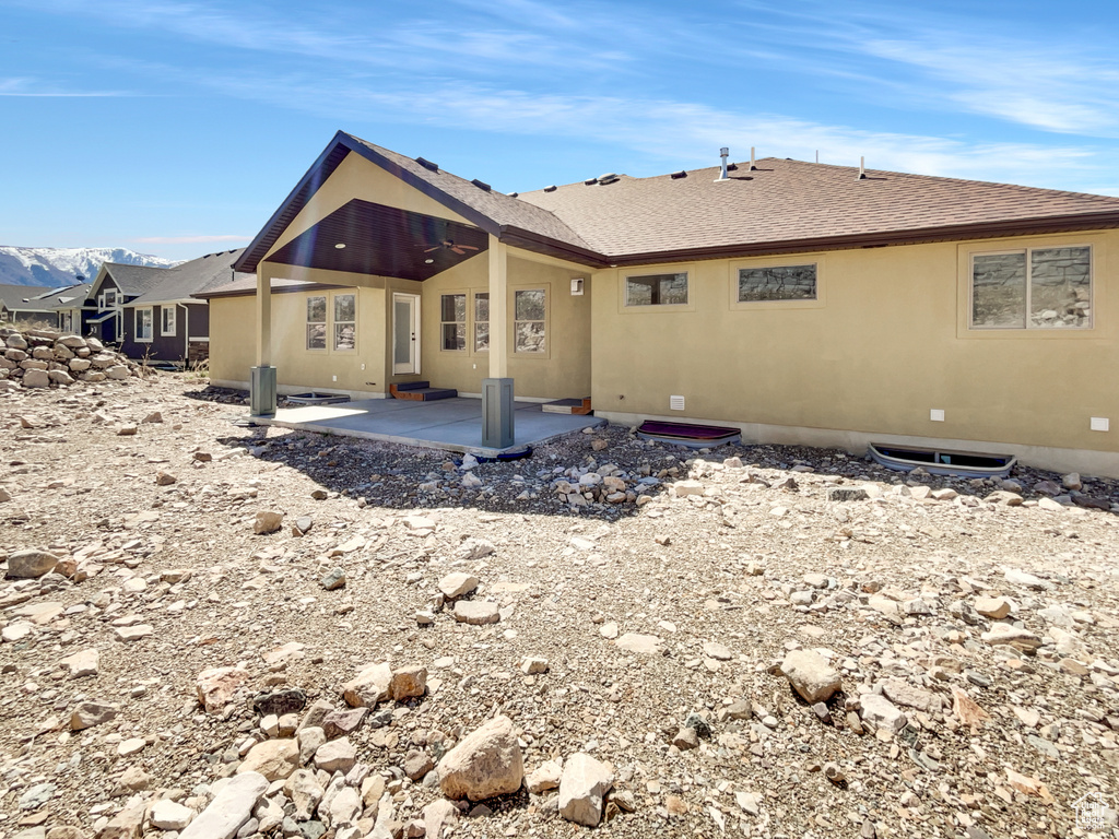 Back of house featuring roof with shingles, a patio area, and stucco siding