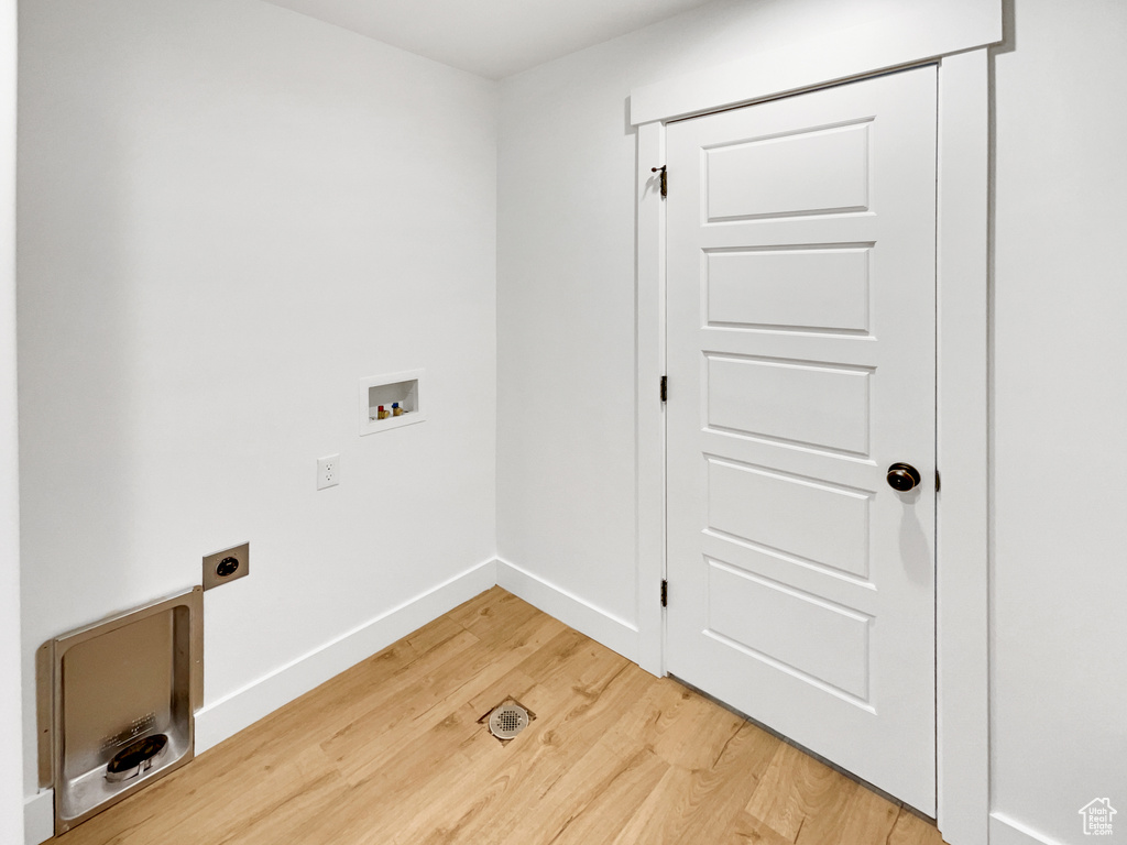 Laundry area featuring baseboards, laundry area, light wood finished floors, electric dryer hookup, and hookup for a washing machine
