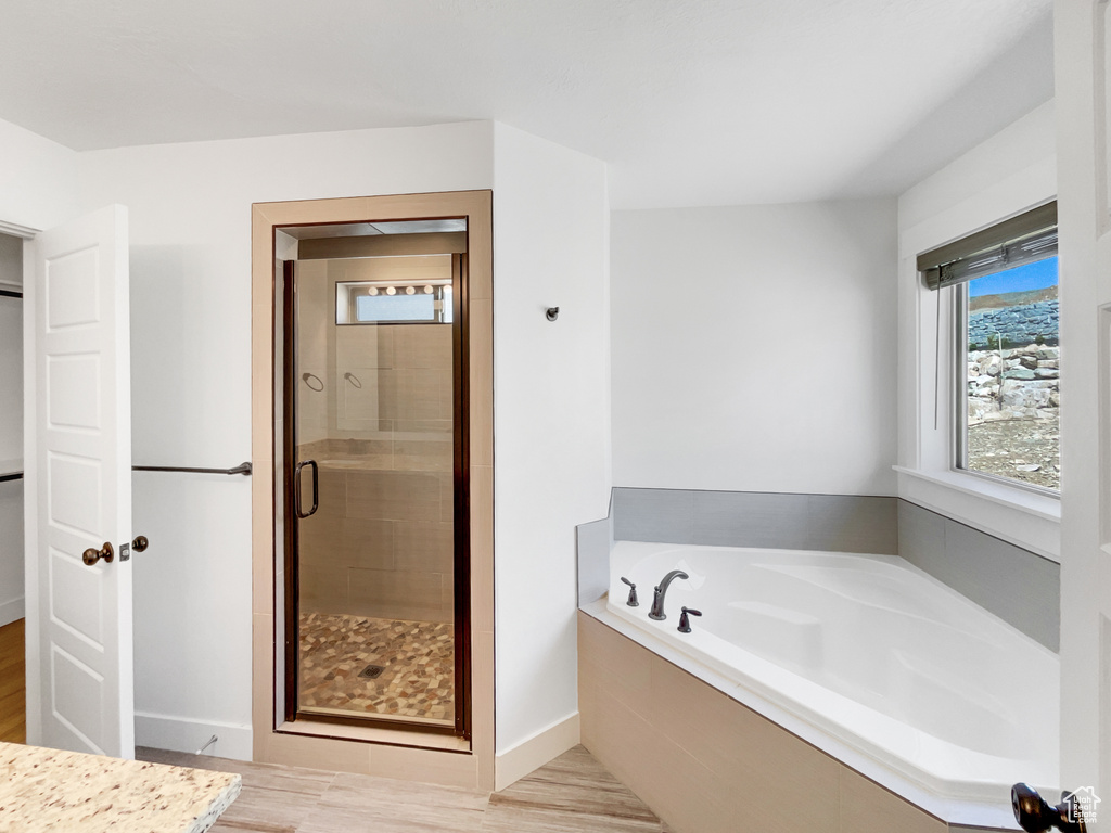 Full bath featuring a shower stall, a bath, wood finished floors, and baseboards