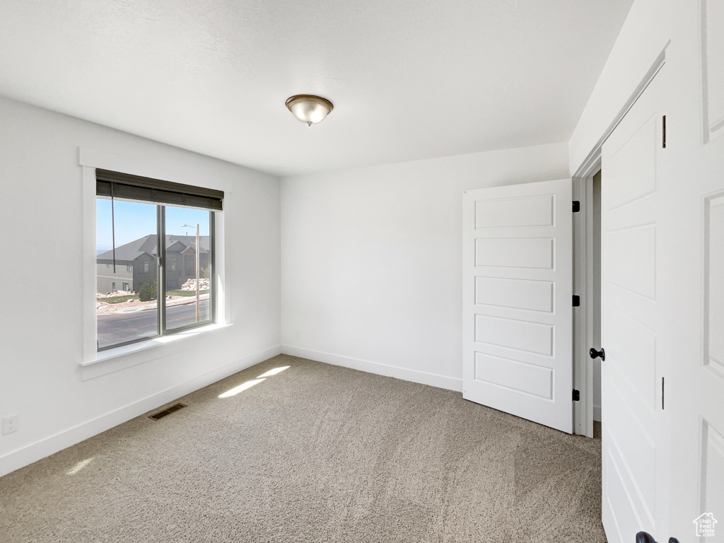 Carpeted empty room with baseboards and visible vents