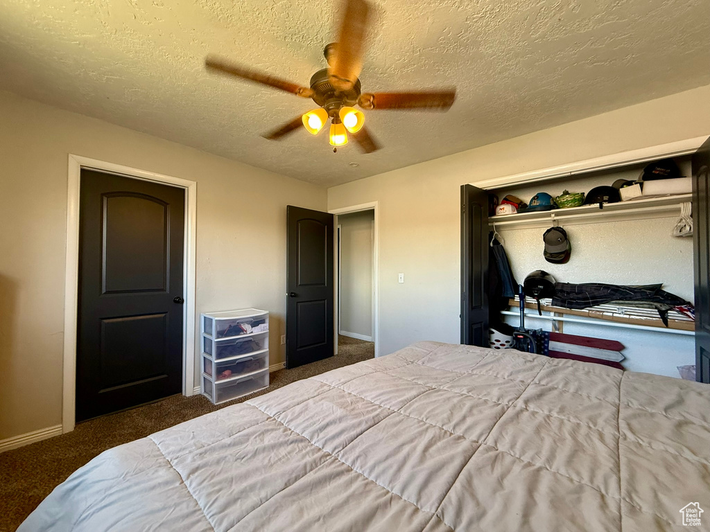 Bedroom with baseboards, carpet floors, a textured ceiling, a closet, and a ceiling fan