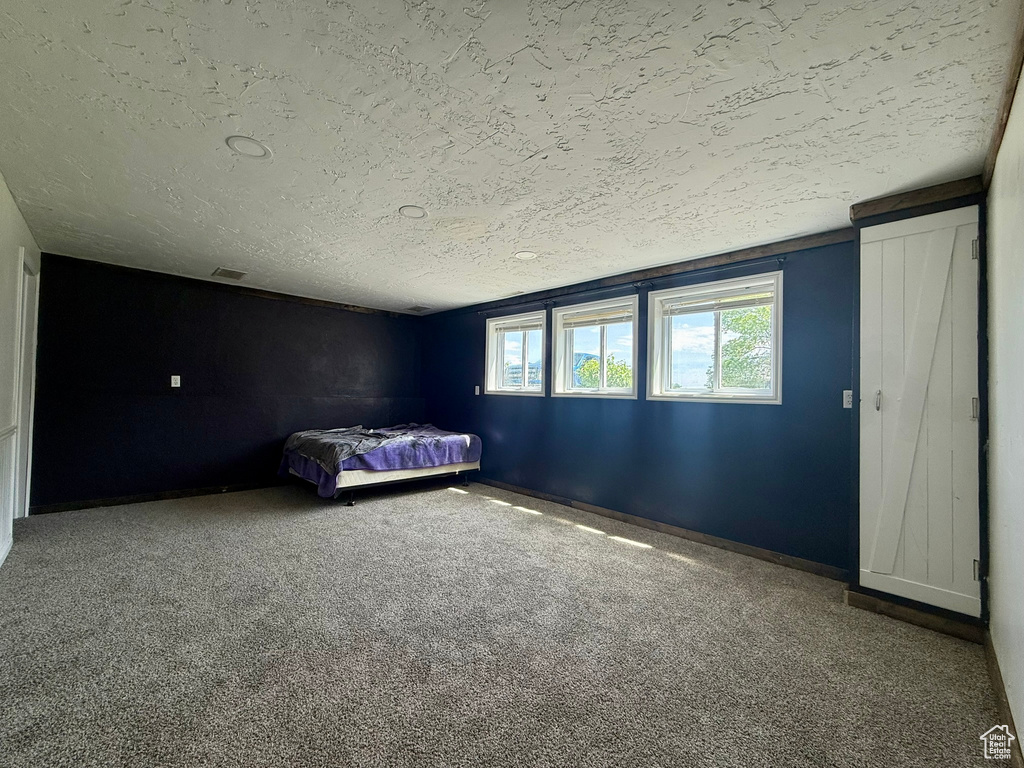 Unfurnished bedroom featuring a textured ceiling, carpet flooring, and baseboards