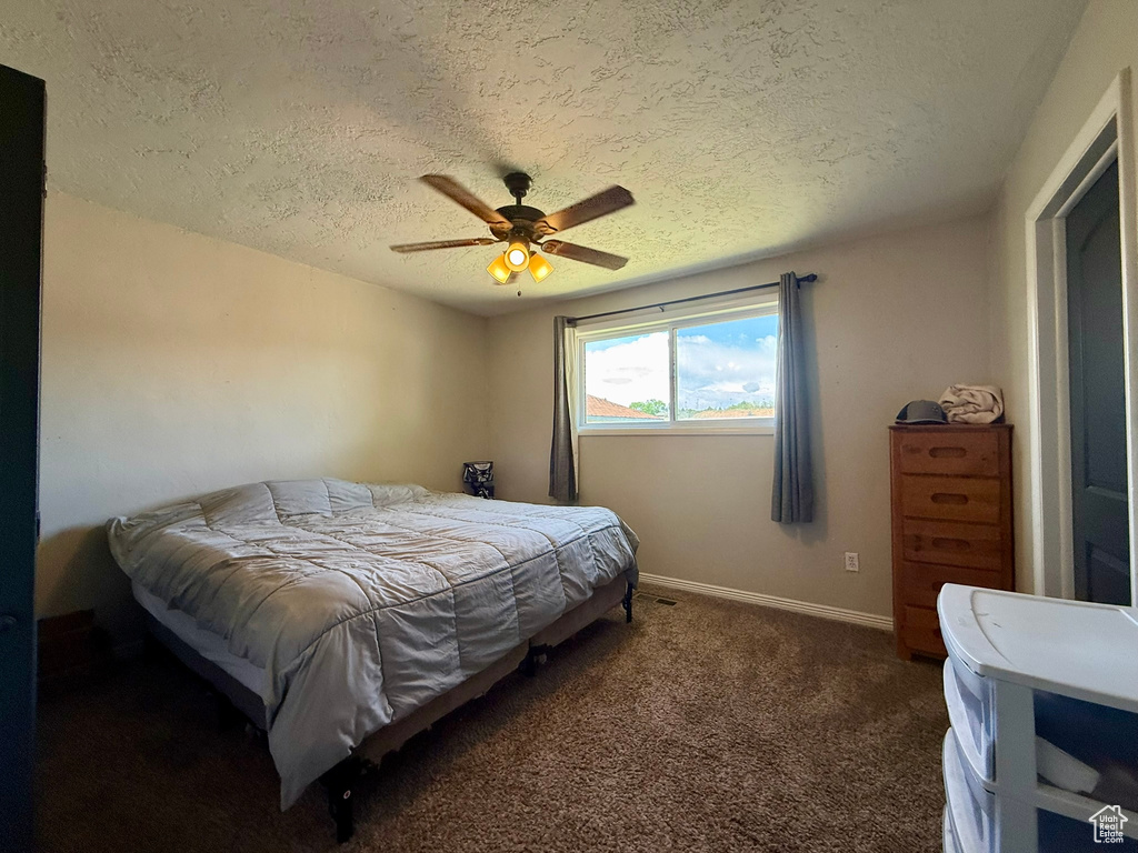 Carpeted bedroom with a textured ceiling, a ceiling fan, and baseboards