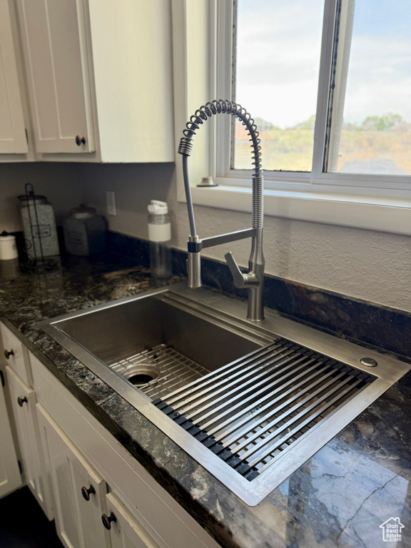 Kitchen view of a sink and white cabinetry