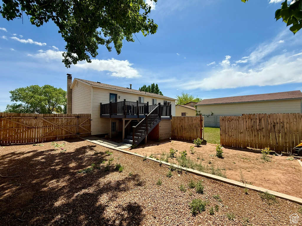 Back of property featuring stairs, a wooden deck, a fenced backyard, a gate, and a chimney
