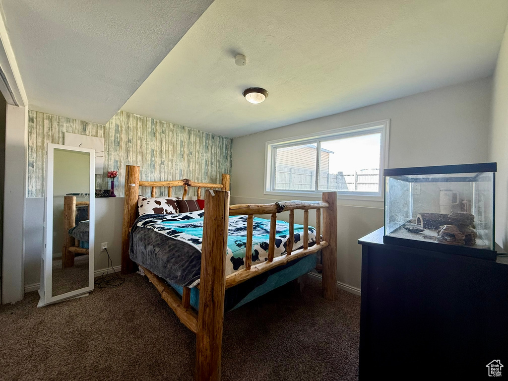 Carpeted bedroom with wallpapered walls, baseboards, and a textured ceiling